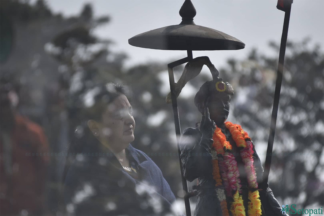 राष्ट्रपति विद्या भण्डारीले सिंहदरबारको मूलगेट अगाडि रहेको राष्ट्र निर्माता पृथ्वीनारायण शाहको शालिकमा माल्यार्पण गरेपछि सलामी ग्रहण गर्दै (नोटः तस्बिर मल्टी एक्पोज प्रयोग गरेर खिचिएको हो)। तस्बिरः नारायण महर्जन।