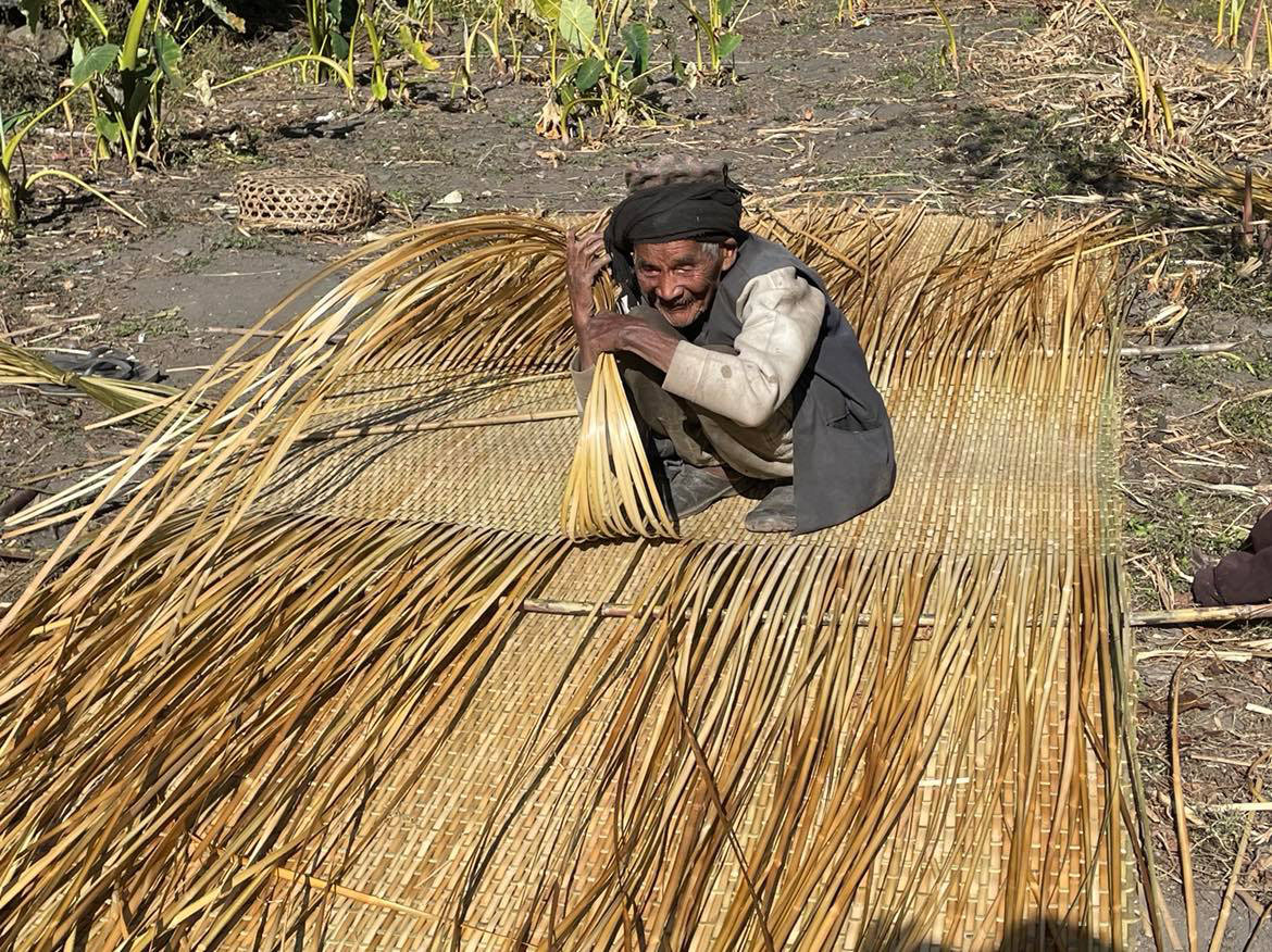 पश्चिम म्याग्दीको धवलागिरि गाउँपालिका– ४ बगरका १०५ वर्षीय पवबहादुर पुर्जा घरको आँगनमा बसेर भकारी बुन्दै। तस्बिरः ध्रुवसागर शर्मा/रासस