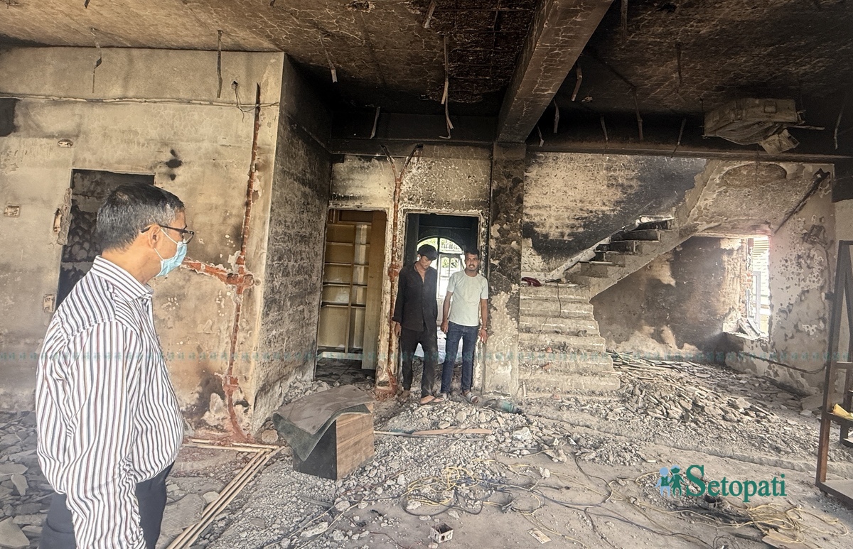 आन्दोलनमा जलाइएको आफ्नो घरभित्रको अवस्था हेर्दै डा. डम्बर खड्का। (बायाँ)